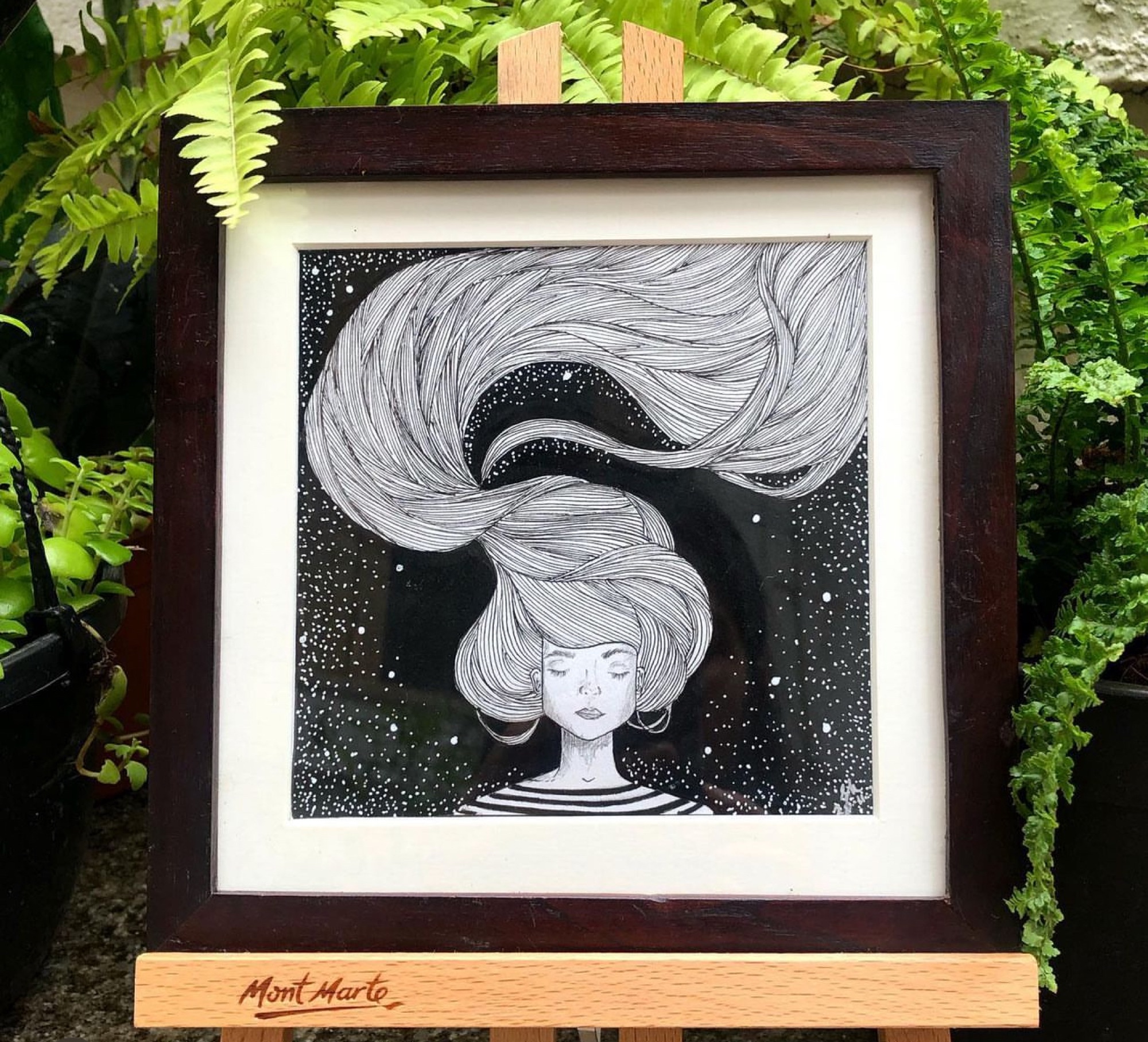 Framed black-and-white pen illustration of a woman with swirling starry hair against a night sky background